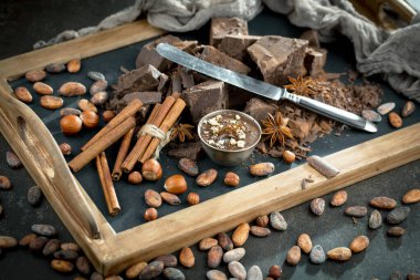 Eskimiş bir arka planda kakao çekirdeği ve fındıklı siyah çikolata..