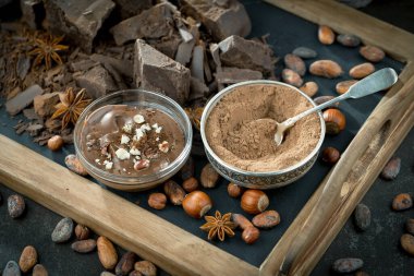 Eskimiş bir arka planda kakao çekirdeği ve fındıklı siyah çikolata..