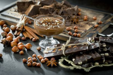 Eskimiş bir arka planda kakao çekirdeği ve fındıklı siyah çikolata..