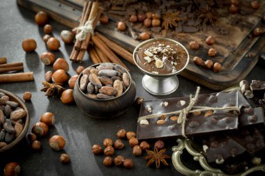 Eskimiş bir arka planda kakao çekirdeği ve fındıklı siyah çikolata..