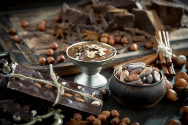 Eskimiş bir arka planda kakao çekirdeği ve fındıklı siyah çikolata..