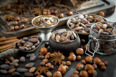 Eskimiş bir arka planda kakao çekirdeği ve fındıklı siyah çikolata..