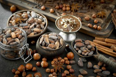 Eskimiş bir arka planda kakao çekirdeği ve fındıklı siyah çikolata..