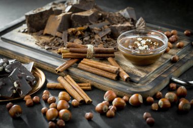 Eskimiş bir arka planda kakao çekirdeği ve fındıklı siyah çikolata..