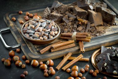 Eskimiş bir arka planda kakao çekirdeği ve fındıklı siyah çikolata..