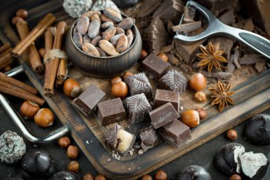 Kakao çekirdeğinin arka planında koyu çikolata ve mutfak malzemeleri.