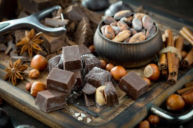 Kakao çekirdeğinin arka planında koyu çikolata ve mutfak malzemeleri.