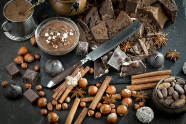 Kakao çekirdeğinin arka planında koyu çikolata ve mutfak malzemeleri.