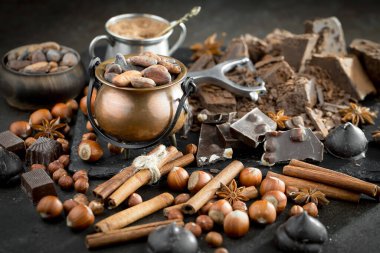 Kakao çekirdeğinin arka planında koyu çikolata ve mutfak malzemeleri.