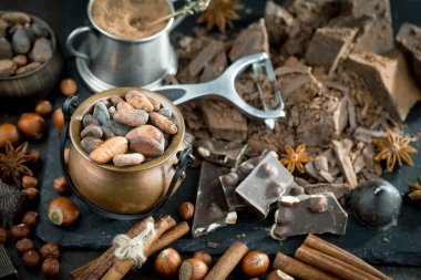 Kakao çekirdeğinin arka planında koyu çikolata ve mutfak malzemeleri.