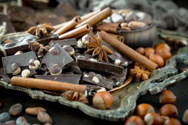 Kakao çekirdeğinin arka planında koyu çikolata ve mutfak malzemeleri.