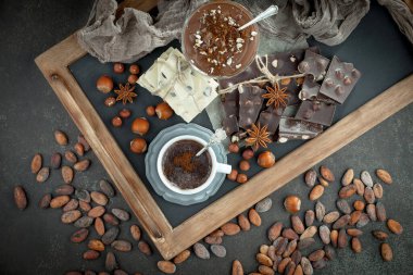 Kakao çekirdeğinin arka planında koyu çikolata ve mutfak malzemeleri.