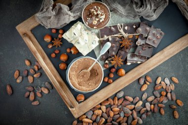 Kakao çekirdeğinin arka planında koyu çikolata ve mutfak malzemeleri.