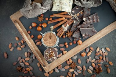 Kakao çekirdeğinin arka planında koyu çikolata ve mutfak malzemeleri.