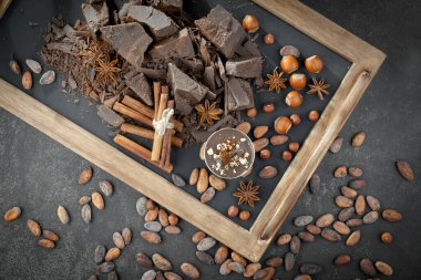 Kakao çekirdeğinin arka planında koyu çikolata ve mutfak malzemeleri.