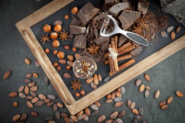Kakao çekirdeğinin arka planında koyu çikolata ve mutfak malzemeleri.