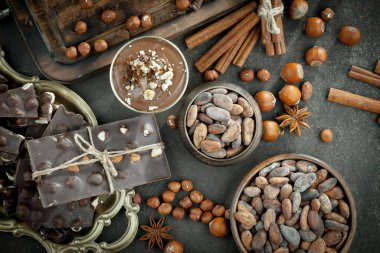 Kakao çekirdeğinin arka planında koyu çikolata ve mutfak malzemeleri.