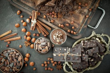 Kakao çekirdeğinin arka planında koyu çikolata ve mutfak malzemeleri.