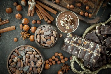 Kakao çekirdeğinin arka planında koyu çikolata ve mutfak malzemeleri.