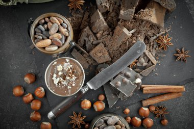 Kakao çekirdeğinin arka planında koyu çikolata ve mutfak malzemeleri.