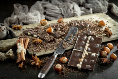 Kakao çekirdeğinin arka planında koyu çikolata ve mutfak malzemeleri.