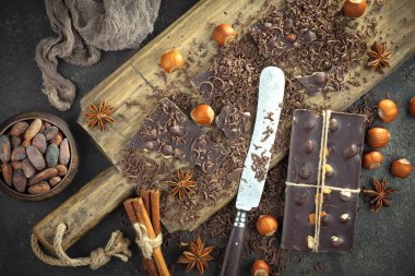 Kakao çekirdeğinin arka planında koyu çikolata ve mutfak malzemeleri.