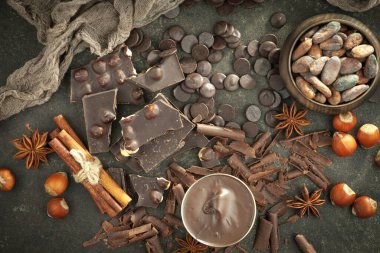 Kakao çekirdeğinin arka planında koyu çikolata ve mutfak malzemeleri.