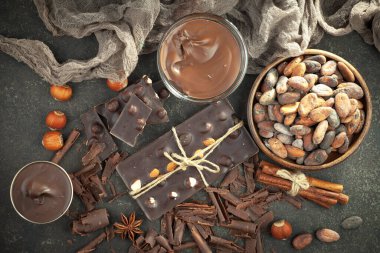 Kakao çekirdeğinin arka planında koyu çikolata ve mutfak malzemeleri.