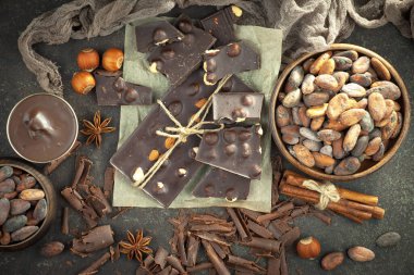 Kakao çekirdeğinin arka planında koyu çikolata ve mutfak malzemeleri.