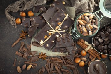 Kakao çekirdeğinin arka planında koyu çikolata ve mutfak malzemeleri.