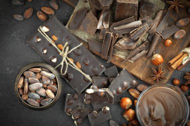 Kakao çekirdeğinin arka planında koyu çikolata ve mutfak malzemeleri.