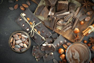 Kakao çekirdeğinin arka planında koyu çikolata ve mutfak malzemeleri.
