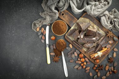 Kakao çekirdeğinin arka planında koyu çikolata ve mutfak malzemeleri.