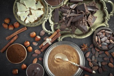 Kakao çekirdeğinin arka planında koyu çikolata ve mutfak malzemeleri.