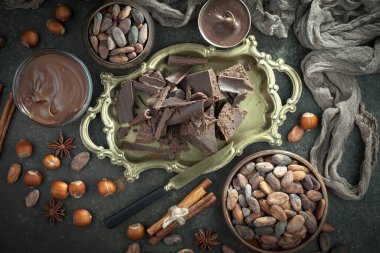 Kakao çekirdeğinin arka planında koyu çikolata ve mutfak malzemeleri.