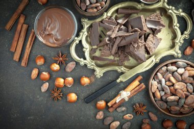 Kakao çekirdeğinin arka planında koyu çikolata ve mutfak malzemeleri.