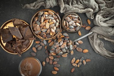 Kakao çekirdeğinin arka planında koyu çikolata ve mutfak malzemeleri.