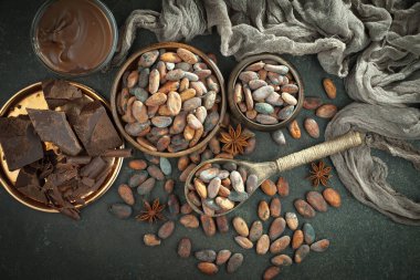 Kakao çekirdeğinin arka planında koyu çikolata ve mutfak malzemeleri.