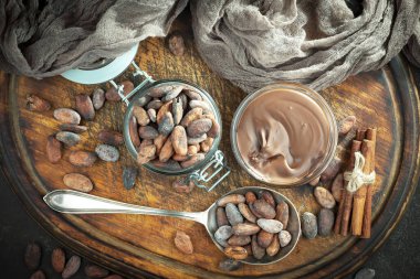 Kakao çekirdeğinin arka planında koyu çikolata ve mutfak malzemeleri.