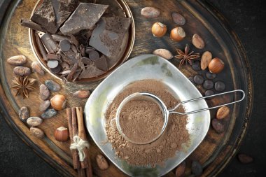 Kakao çekirdeğinin arka planında koyu çikolata ve mutfak malzemeleri.