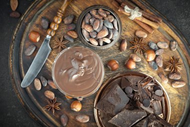 Kakao çekirdeğinin arka planında koyu çikolata ve mutfak malzemeleri.