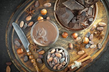 Kakao çekirdeğinin arka planında koyu çikolata ve mutfak malzemeleri.