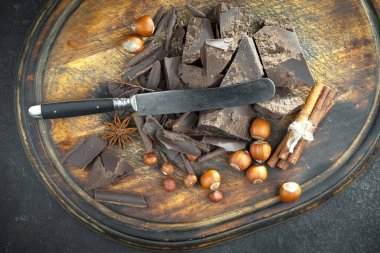 Kakao çekirdeğinin arka planında koyu çikolata ve mutfak malzemeleri.