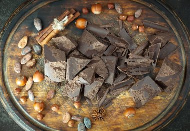 Kakao çekirdeğinin arka planında koyu çikolata ve mutfak malzemeleri.