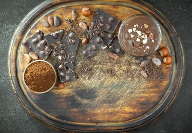 Kakao çekirdeğinin arka planında koyu çikolata ve mutfak malzemeleri.