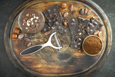 Kakao çekirdeğinin arka planında koyu çikolata ve mutfak malzemeleri.