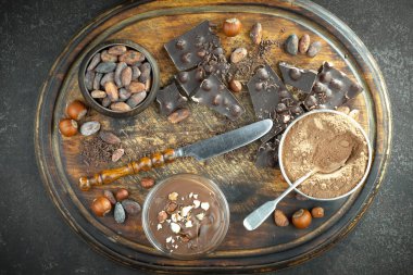 Kakao çekirdeğinin arka planında koyu çikolata ve mutfak malzemeleri.