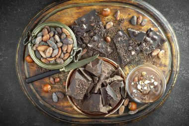 Kakao çekirdeğinin arka planında koyu çikolata ve mutfak malzemeleri.