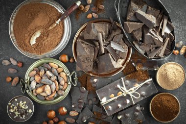 Kakao çekirdeğinin arka planında koyu çikolata ve mutfak malzemeleri.