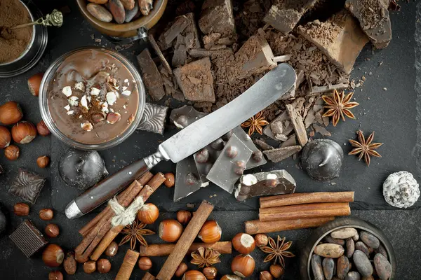 Kakao çekirdeğinin arka planında koyu çikolata ve mutfak malzemeleri.